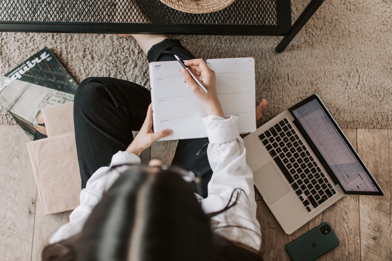 Faceless lady with notebook and laptop on floor at home