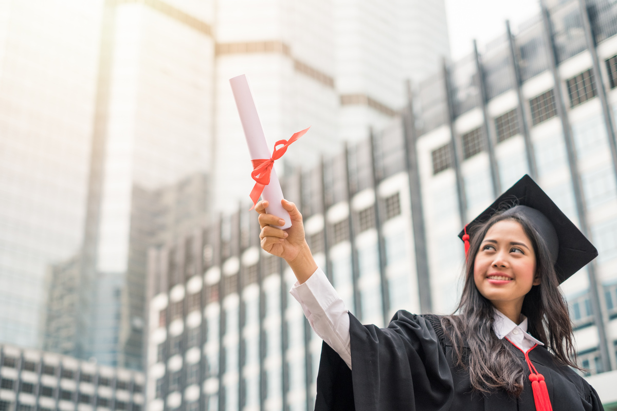 Woman wearing gown raising hand with success Bachelor Degree