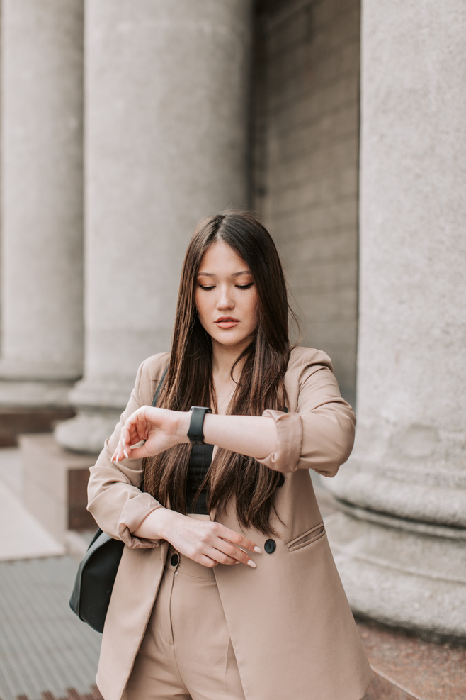 Woman in Beige Corporate Attire Looking at the Time on Her Wristwatch